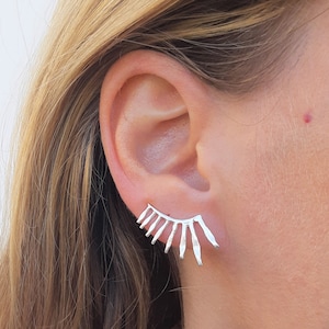 Puede incluir: Pendientes de aro de plata con un diseño geométrico. Los pendientes tienen forma de abanico y un borde puntiagudo.