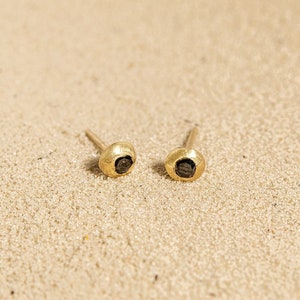 May include: A pair of gold stud earrings with small black gemstones in the centre.