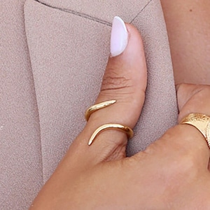 Peut inclure: Une bague en or en forme de serpent avec un design incurvé. La bague est portée au pouce.