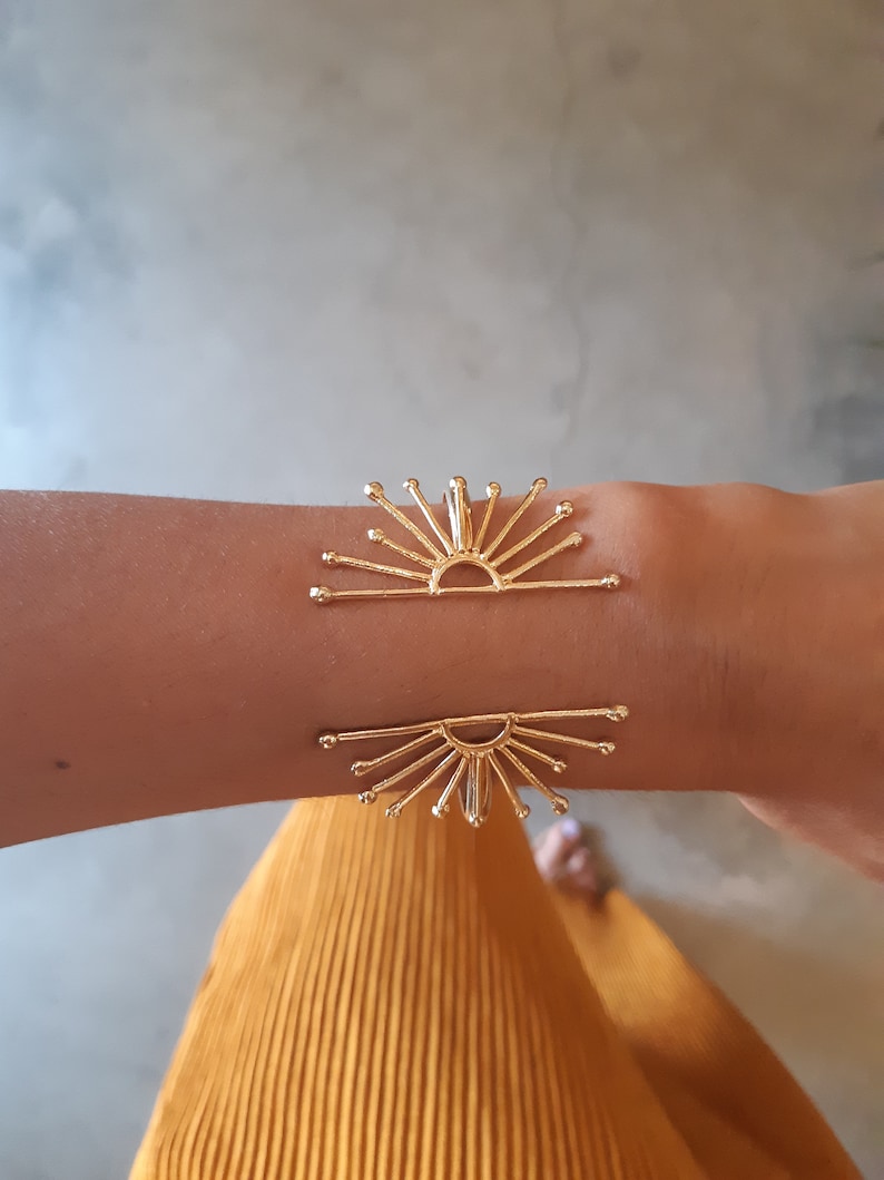 K&ouml;nnte beinhalten: Goldenes Sonnenstrahlen-Armband mit einem zarten Design. Das Armband ist offen und verstellbar, um an die meisten Handgelenke zu passen.