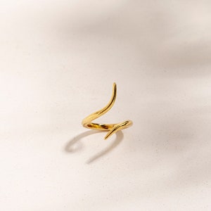 Peut inclure: Une bague en or avec un design unique et torsadé. La bague est en métal et a une finition lisse et polie.