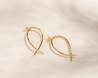 May include: A pair of gold-toned hoop earrings with a unique, curved design. The earrings are made of a thin, delicate wire and have a simple, elegant look.