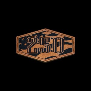 May include: A brown and black patch with the number "250" in a bold, vintage font. The background features a stylized American flag design with stars and stripes. The patch has a stitched border.