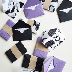 May include: A collection of small, decorative envelopes in various colors and patterns. The envelopes are made of paper and have a variety of designs, including floral, geometric, and abstract patterns. Some of the envelopes are plain, while others have a textured finish. The envelopes are all closed and ready to be used for sending letters or notes.