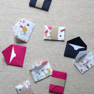 May include: Assortment of colorful envelopes with floral and geometric patterns. Some envelopes are closed with a brown paper band.