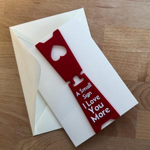 Un piccolo segno "Ti amo di più" - Biglietto d'amore con mini cartello staccabile