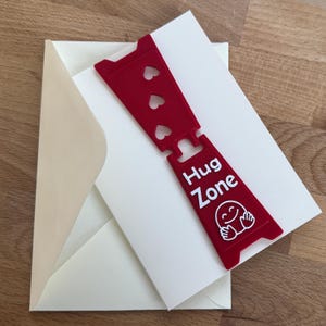 HUG Zone - Agora você corre o risco de ser abraçado - Cartão de Amor com Mini Placa Destacável