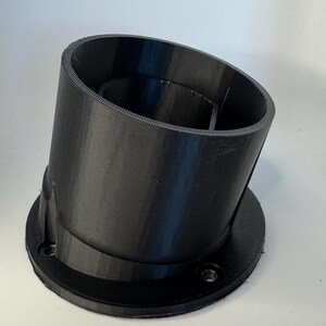 May include: A black plastic 3D printed object with a cylindrical shape and a circular base. The object has a small opening at the top and a series of ridges around the outside.