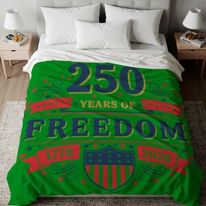 a bed with a green comforter that has a large text design celebrating the 250th anniversary of the United States.