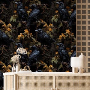 May include: A dark wallpaper featuring black ravens perched on branches amidst foliage with yellow flowers. A light wood cabinet with a woven front and curved sides is in front of the wallpaper. Decorative vases and a lamp sit on top.