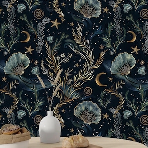 Puede incluir: Un papel tapiz azul oscuro con un patrón repetitivo de algas doradas y verdes, conchas y estrellas. El papel tapiz se muestra en una mesa con un jarrón blanco y una hogaza de pan.