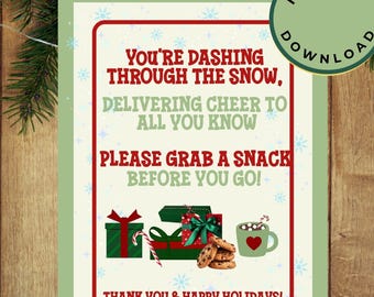 Puede incluir: Un letrero festivo navideño con fondo crema y borde rojo. El letrero presenta texto que dice: "¡Te estás lanzando por la nieve... Por favor, toma un refrigerio antes de irte!" con ilustraciones de regalos, galletas y chocolate caliente.