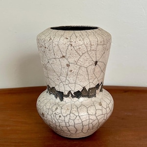 May include: A white ceramic vase with a crackled glaze and a brown band around the middle. The vase has a rounded base and a flared top.