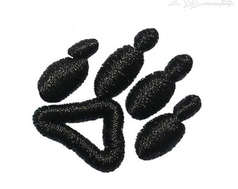 May include: Black embroidered paw print design. The paw print is made up of five individual shapes, each with a textured surface.