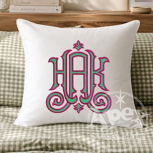 May include: A square white throw pillow featuring a central embroidered monogram with the letters HAK. The design uses a vibrant combination of hot pink and bright green thread, showcasing intricate scrollwork and decorative flourishes.