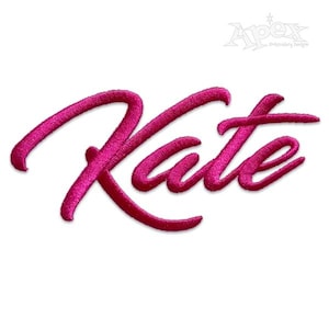 May include: A vibrant fuchsia embroidered patch featuring the name "Kate" in a flowing, cursive style. The stitching creates a textured effect, with the name presented in a bold font. The Apex Embroidery Designs logo is visible in the top right.