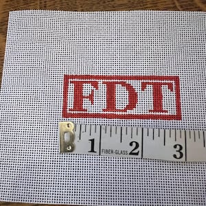 May include: White canvas with a red rectangle containing the text "FDT" in all caps. A measuring tape is placed at the bottom of the canvas, showing the numbers 1, 2, and 3.