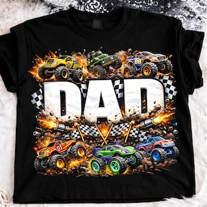 Könnte beinhalten: Schwarzes T-Shirt mit einem farbenfrohen Monster-Truck-Motiv und dem Wort "DAD" in Weiß. Das Design umfasst karierte Flaggen und Flammen, wodurch eine dynamische und actionreiche Szene entsteht.