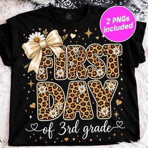 Könnte beinhalten: Ein schwarzes T-Shirt mit dem Text FIRST DAY in großen Buchstaben mit Leopardenmuster, die mit weißen Gänseblümchen verziert sind. Eine große cremefarbene Schleife befindet sich auf der linken Seite. 3rd grade steht in weißer Schreibschrift darunter.