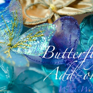 May include: Close-up of several decorative butterfly add-ons in shades of blue, teal, and gold. The butterflies are made of sheer, shimmering fabric with intricate details and gold accents. The text "Butterfly Add-on!" is visible.