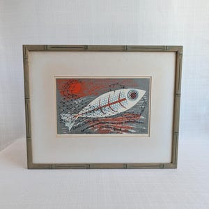 May include: A framed print featuring a stylized white fish with a red skeletal pattern, a large eye, and a black net overlay against a grey background with a red sun. The text reads: little silver fish, pointing upstream moving downstream in clear quick water.