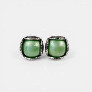 May include: A pair of square stud earrings. Each earring has a light green, pearlescent centre, framed by a silver-toned, rope-style border. The earrings are set against a white background.