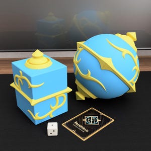 May include: A light blue and yellow cube-shaped container and a matching spherical container, both featuring raised yellow filigree details. A small white six-sided die and a rectangular black and gold Palworld Official Card Game card are included.