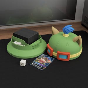 May include: A green card and dice holder with a matching hat-shaped container. The holder has a circular base with a compartment for cards and dice. The hat-shaped container is green with tan ears, orange goggles, and a blue plume. A card and dice are also present.