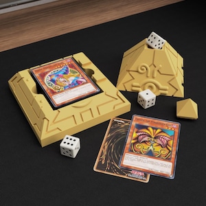 May include: A set of three ceramic mugs with a speckled, cream-coloured glaze. Each mug features a different hand-painted design: a blue and green leaf, a yellow flower, and a red berry. The mugs have a simple, modern design.