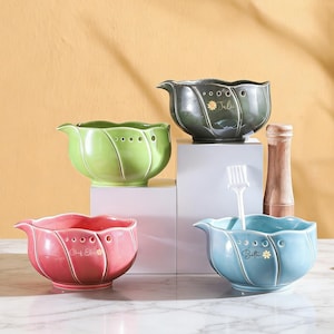 以下が含まれることがあります： 緑、ピンク、青、濃い緑色の4つのセラミックボウル。各ボウルは、注ぎ口と小さな穴を備えたユニークな花の模様です。ボウルにはテキストと花のグラフィックが側面にあります。白いフォークと木製のペッパーグラインダーも表示されます。