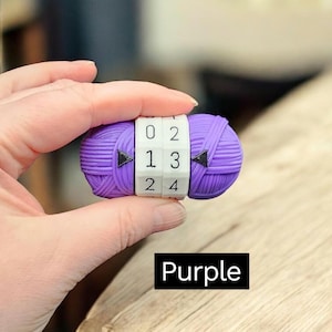 May include: A purple yarn-shaped combination lock with white number dials. The dials display numbers 0-4. The word "Purple" is in a black rectangle at the bottom of the image.