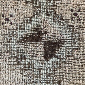 May include: A brown and white patterned rug with a geometric design. The rug has a distressed look and is made of woven fibers.