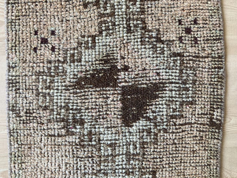 May include: A brown and white patterned rug with a geometric design. The rug has a distressed look and is made of woven fibers.