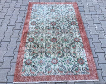 May include: A vintage rug with a floral pattern in shades of red, green, and white. The rug has a faded, distressed look and a red border.