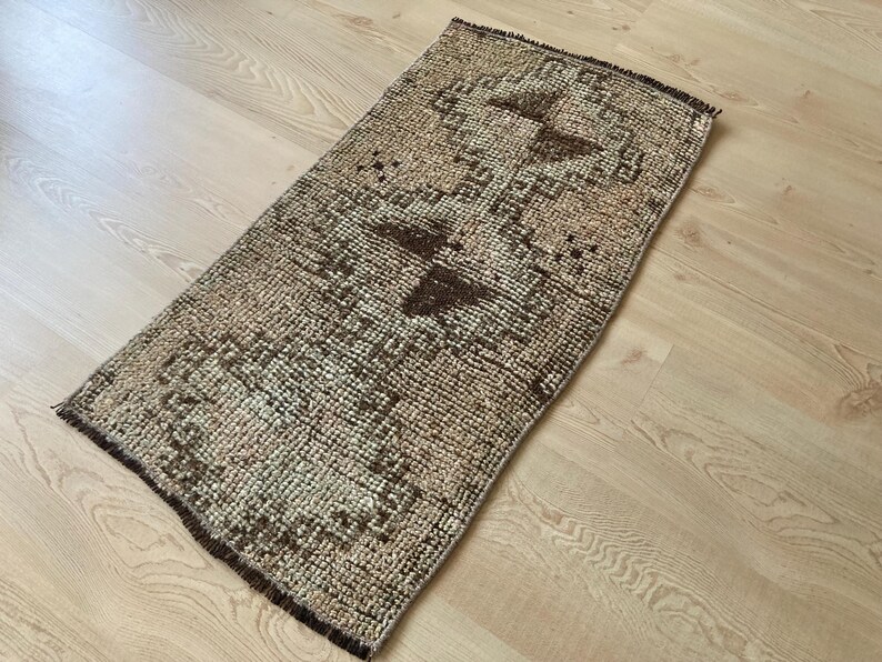 May include: A small, rectangular rug with a brown and beige geometric pattern. The rug has a distressed, vintage look.