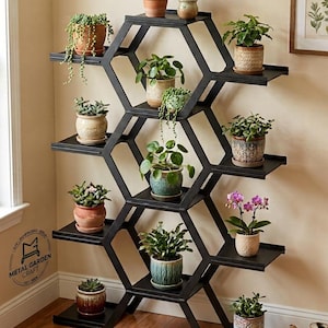 Pode incluir: Um suporte para plantas em metal preto com um design modular em favo de mel e várias prateleiras planas. A estrutura sustenta várias plantas em vasos, incluindo suculentas, plantas pendentes e uma pequena orquídea, na armação hexagonal.