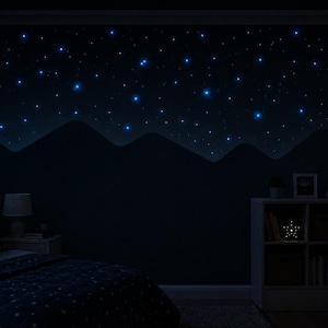 Op de afbeelding: Een donkere slaapkamer met een sterrenhemelthema. De muur heeft een geschilderde bergketen en gloeiende blauwe sterren. Een bed met een sterrenpatroon dekbedovertrek, een nachtkastje met een lamp en een boekenplank met een stervormig licht.