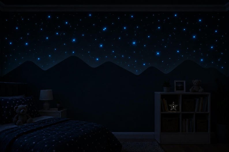 Op de afbeelding: Een donkere slaapkamer met een sterrenhemelthema. De muur heeft een geschilderde bergketen en gloeiende blauwe sterren. Een bed met een sterrenpatroon dekbedovertrek, een nachtkastje met een lamp en een boekenplank met een stervormig licht.