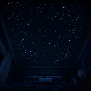 Op de afbeelding: Een donker plafond in de slaapkamer is versierd met gloeiende blauwe en witte sterren, waardoor een sterrenhemel ontstaat. De kamer bevat een bed met kussens en een lamp.