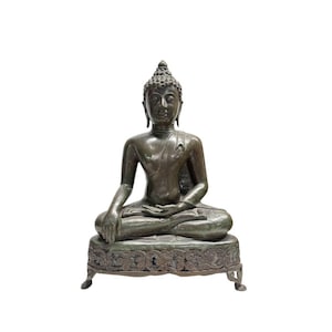 Op de afbeelding: Een bronzen Boeddha-beeld in een zittende meditatiehouding. Het beeld heeft een gedetailleerd gezicht en zit op een sierlijke basis. Het beeld heeft een donkerbronzen kleur en staat tegen een witte achtergrond.
