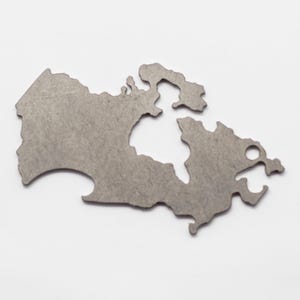 May include: A metal keychain shaped like the outline of Canada. The keychain has a bottle opener on the bottom right side.