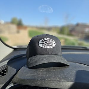 May include: Black baseball cap with a white embroidered patch that says "F*ck Around Find Out" and a black knuckle duster design.
