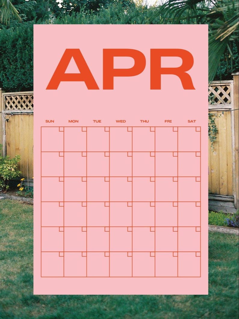 May include: A pink calendar for April with orange lettering and grid lines. The word "APR" is at the top, with days of the week across the top row. The calendar is set against a backdrop of green foliage and a wooden fence.