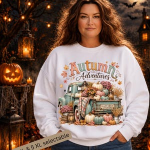 May include: A white crewneck sweatshirt featuring a graphic print of a vintage teal pickup truck filled with pumpkins, flowers, and lanterns. The text Autumn Adventures is printed above the truck, with autumn leaves scattered around the design.