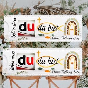 Peut inclure: Deux cartes rectangulaires blanches avec le texte "Sch&ouml;n dass" et "du da bist" en noir et rouge. Les cartes pr&eacute;sentent &eacute;galement un arc-en-ciel, des poissons et les mots "Glaube, Hoffnung, Liebe".