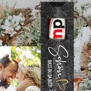 May include: A dark gray felt gift box, 5cm wide and 14cm tall, with the word "du" in a red and white design. The box has the words "Sch&ouml;n, dass du da bist!" in white script with a gold heart.