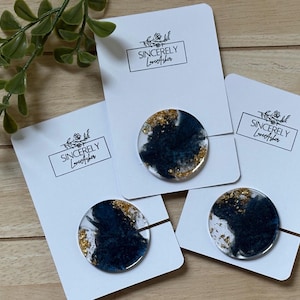 May include: Three round resin phone grips with a dark blue and gold leaf design, attached to white cards. The cards have the text "Sincerely Love Asher" in a rectangular box.