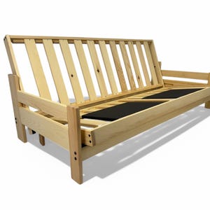 K&ouml;nnte beinhalten: Ein hellfarbiger Futonrahmen aus Holz mit Lattenrost und Armlehnen. Der Rahmen hat eine nat&uuml;rliche Oberfl&auml;che und verf&uuml;gt &uuml;ber zwei schwarze St&uuml;tzplatten. Der Futon ist zum Sitzen und Schlafen konzipiert.