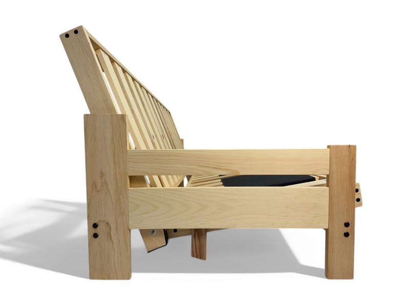 K&ouml;nnte beinhalten: Seitenansicht eines hellen Holz-Futonrahmens. Der Rahmen hat eine Lattenlehne und Armlehnen, mit einem dunklen Kissen sichtbar. Das Design ist schlicht und modern, geeignet f&uuml;r ein Wohn- oder G&auml;stezimmer.