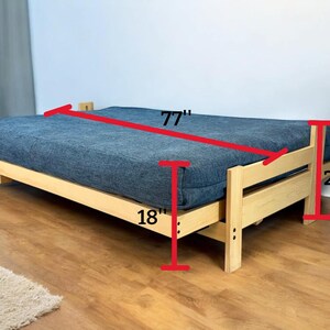 K&ouml;nnte beinhalten: Ein Holz-Futonrahmen mit einer blauen Matratze. Das Futon ist 196 cm lang, 53 cm hoch und 46 cm tief. Der Rahmen besteht aus hellfarbigem Holz.